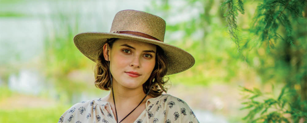 woman in a straw bolero hat standing on a field