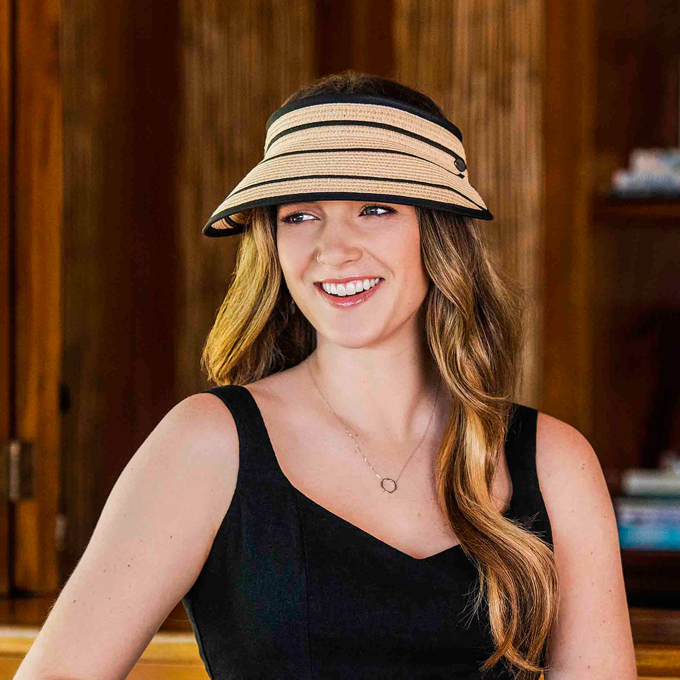 Woman wears a small size sun visor hat made for petite heads. Natural color visor with black stripes