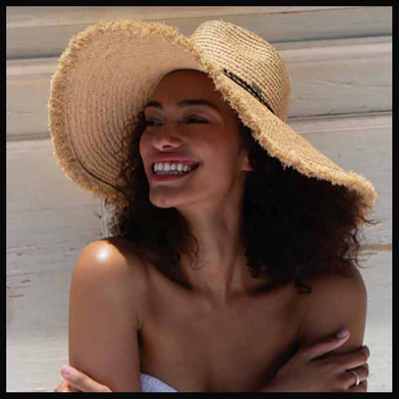 Women wearing a large frayed edge raffia hat. Raffia hat collection at SetarTrading. Natural raffia hats for men and women.