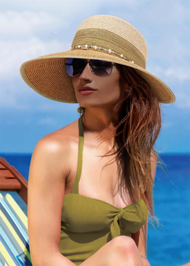 Backless hats, no back hat style. Women in metallic stripe facesaver hat on a lounge chair by the sea