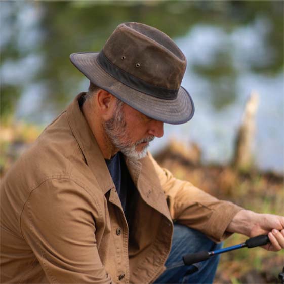 man wears a weathered cotton hat while fishing