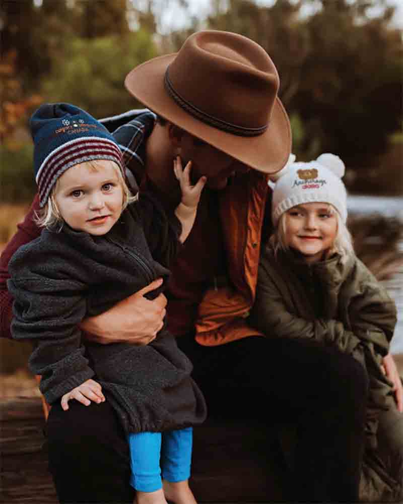 kids winter hats. Father is sitting with two kid wearing warm knit beanie hats